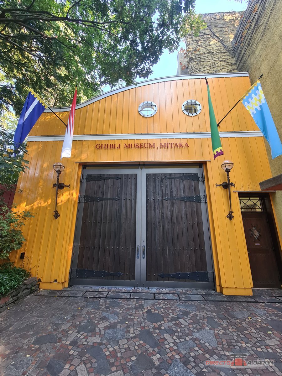 Fachada amarilla del Museo Ghibli de Mitaka con su rótulo y las banderas de colores.