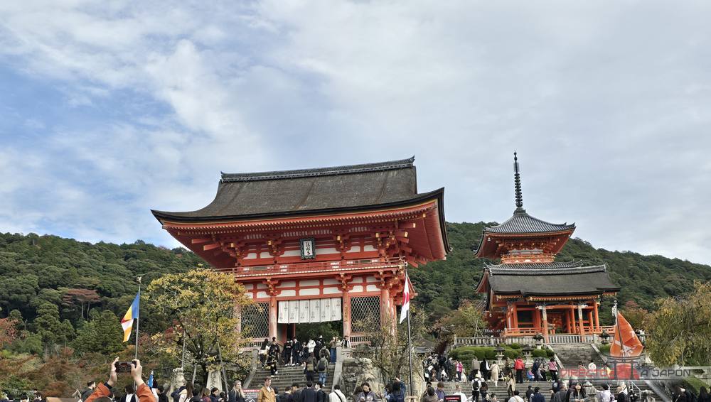 Puerta Niomon de Kiyomizudera, roja y con tejado oscuro, y a la derecha la puerta Saimon con la pagoda de tres pisos detrás, con la explanada llena de visitantes.