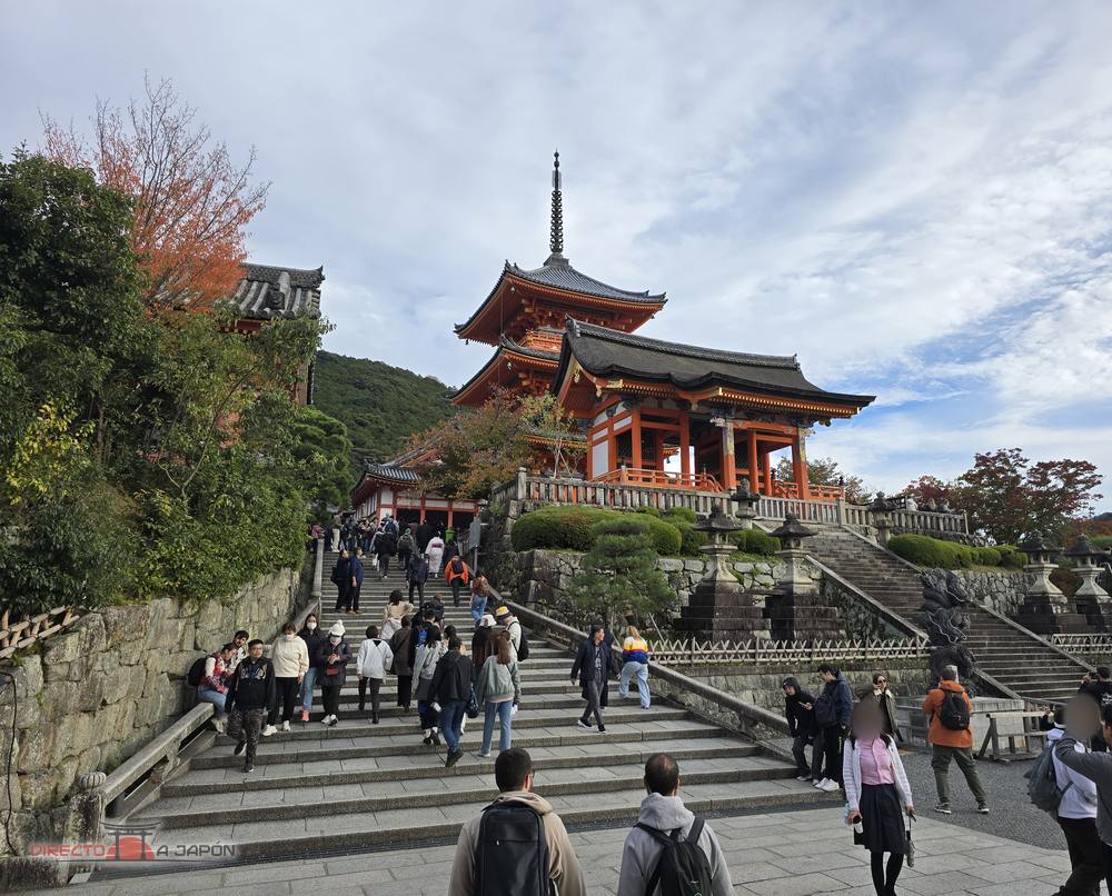 Escalinata de piedra que sube hasta el Saimon, la puerta oeste de color rojo de Kiyomizudera, con la pagoda de tres pisos asomando detrás.